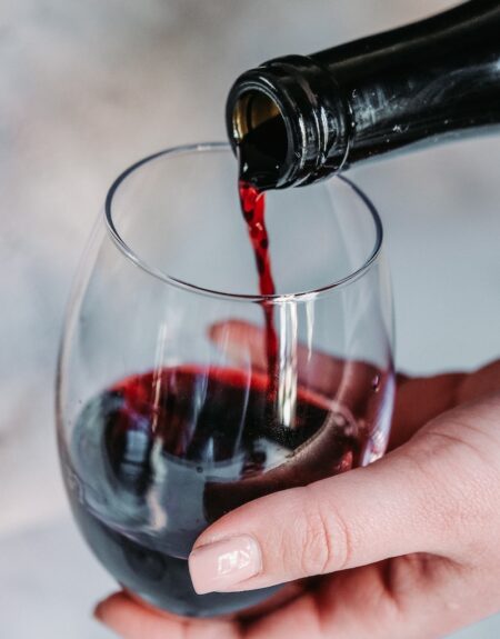 person pouring wine on clear wine glass